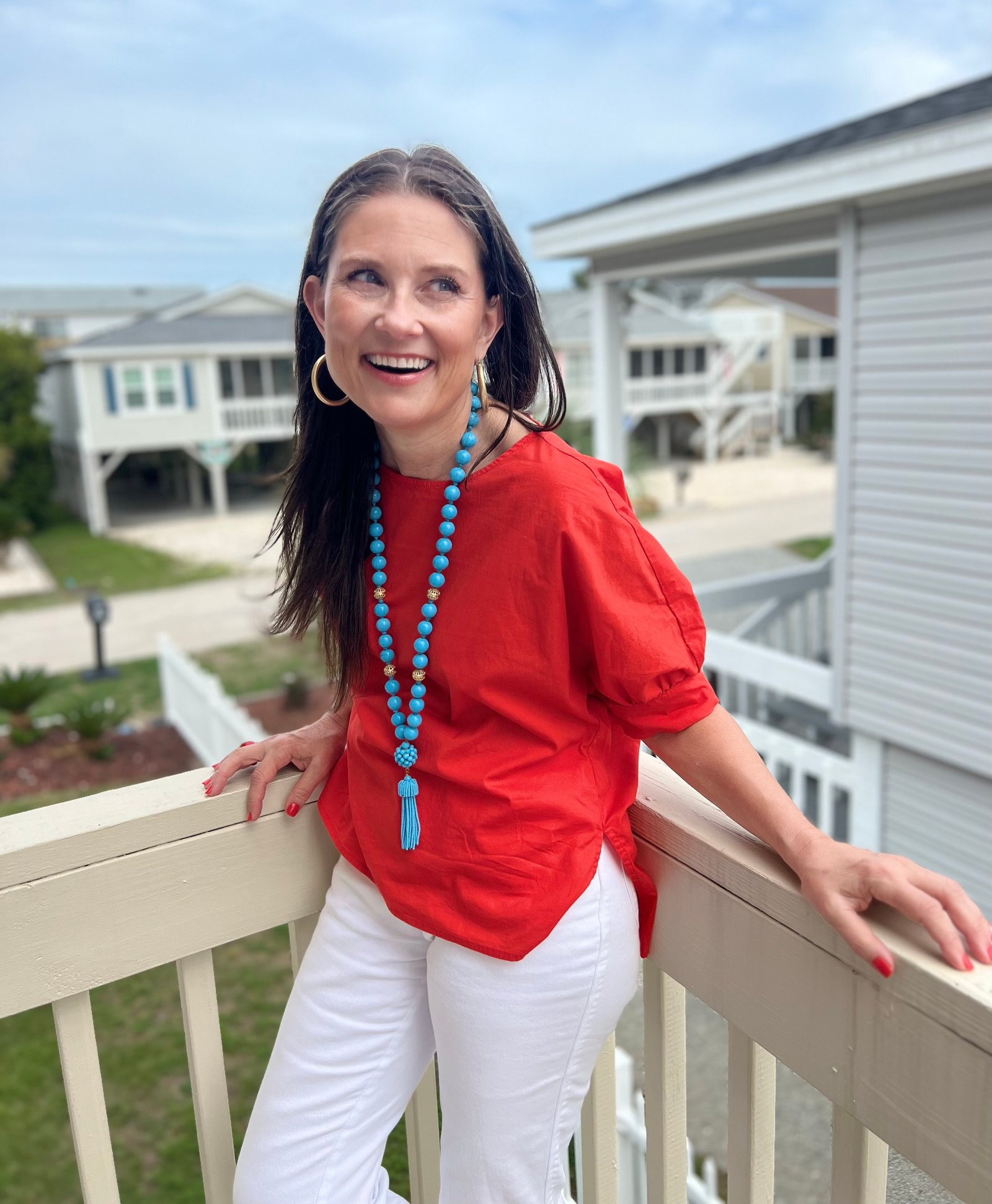 Jess Dauray, principal and lead designer of Jessica Dauray Interiors, smiling on a sunlit porch