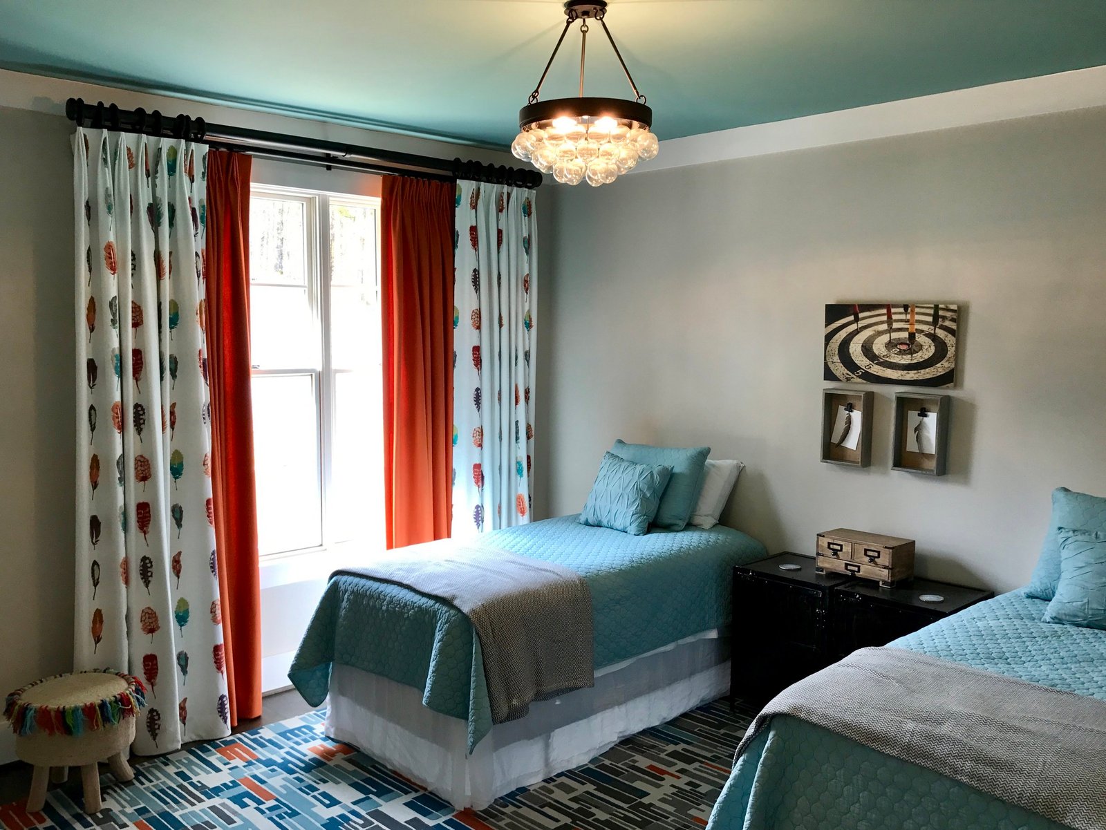 Guest room with twin beds in aqua, a teal ceiling, a crystal chandelier and patterned drapery with persimmon panels