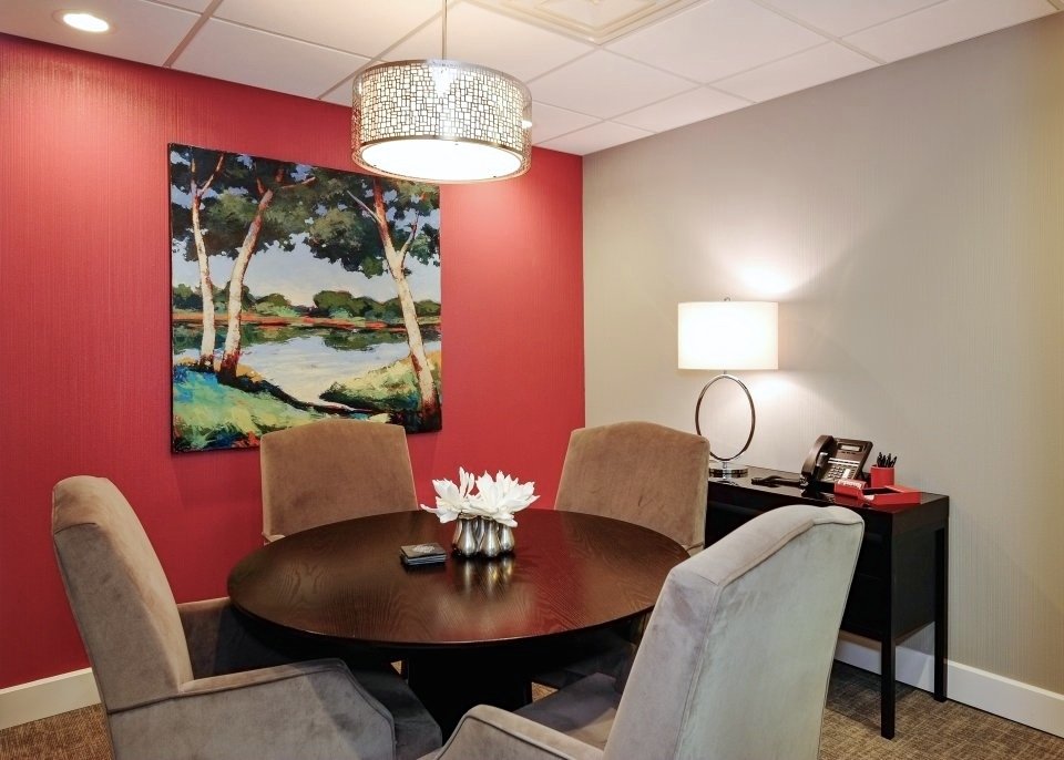 Law office meeting area with a red feature wall, round table and upholstered chairs