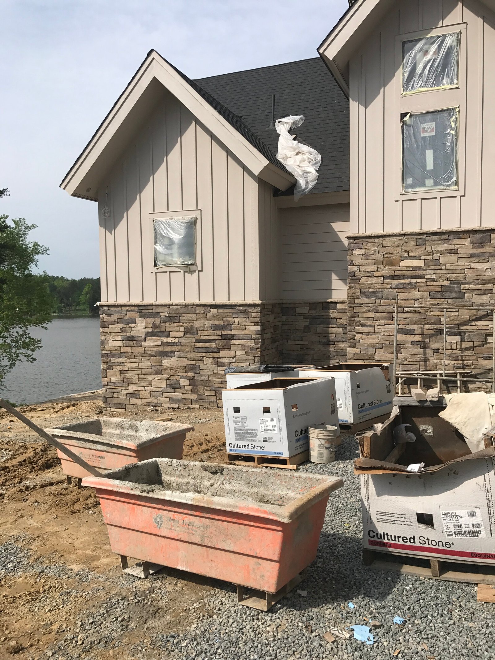 New lakeside home under construction with a stone and board-and-batten facade