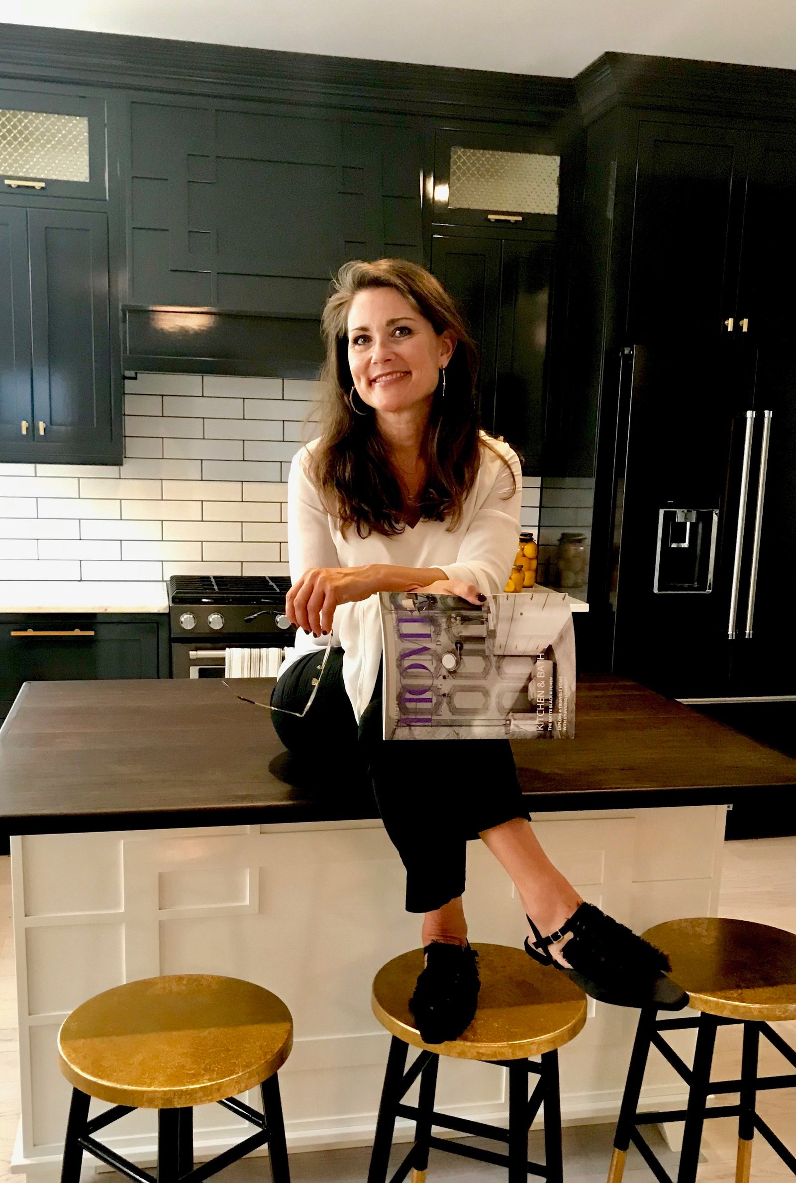 Jess Dauray seated at a kitchen island holding a magazine