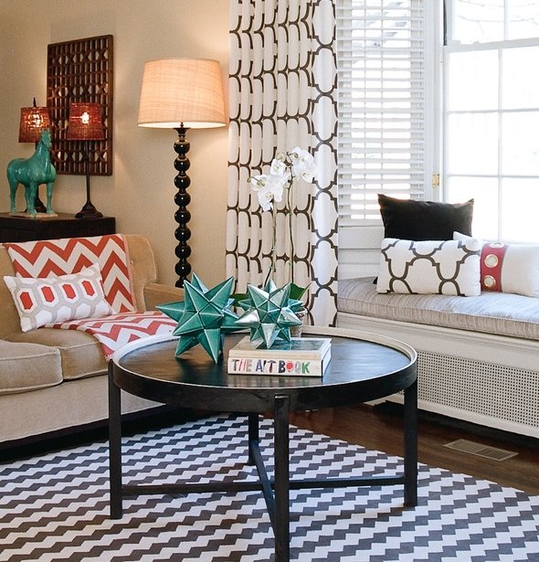 Window seat with graphic pillows beside a black cocktail table styled with turquoise star ornaments