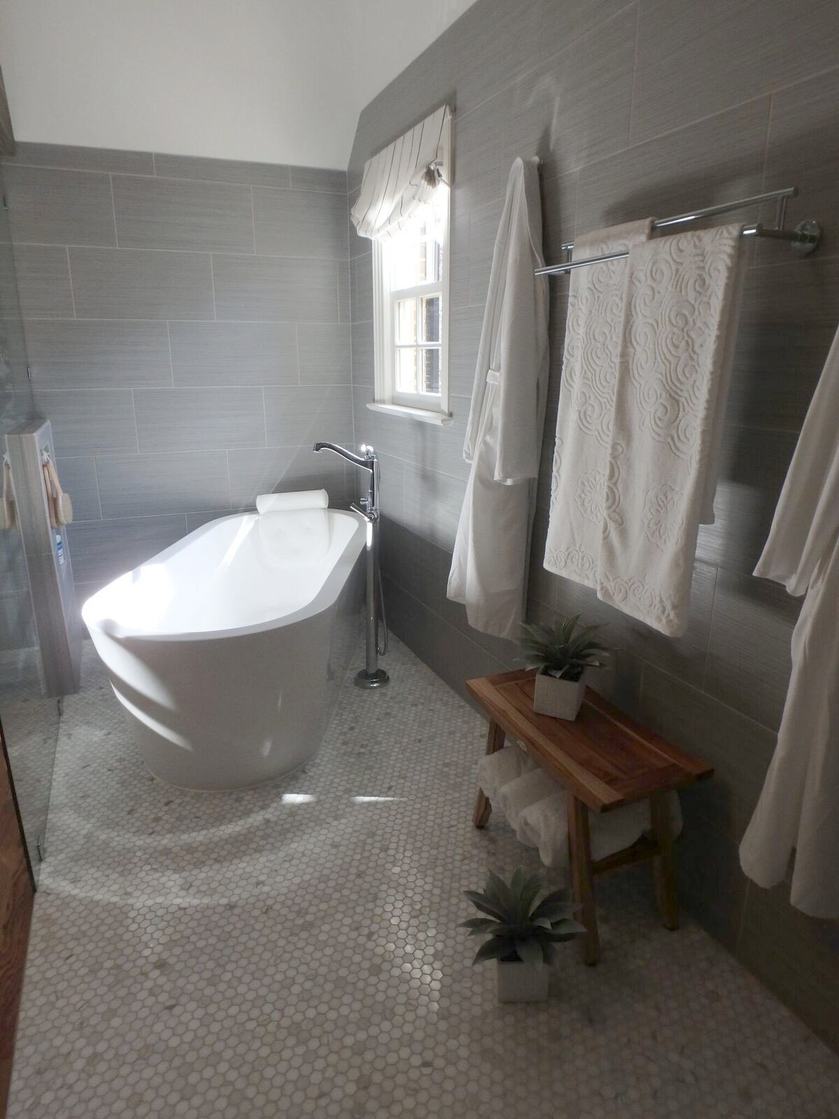 Primary bath with a freestanding tub, marble mosaic floor and gray tile walls