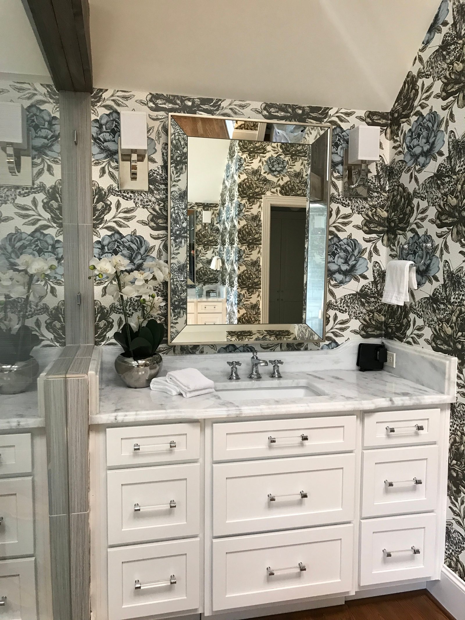 Marble-topped vanity and framed mirror set against a blue-and-white botanical wallcovering