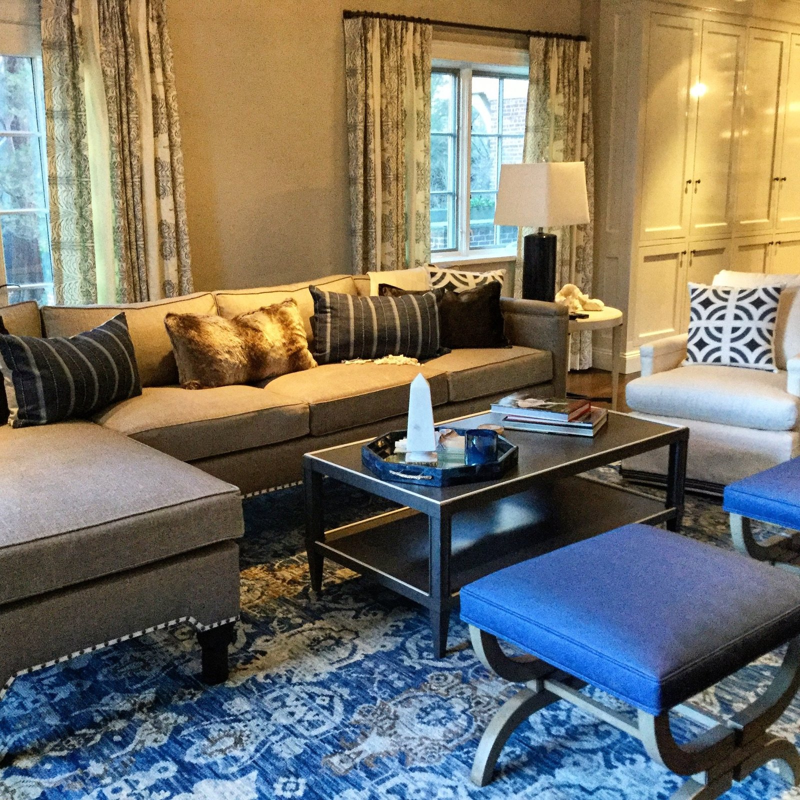 Living room with a sapphire patterned rug, cobalt upholstered stools and a tailored sectional