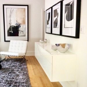 Floating white lacquer console with a white tufted lounge chair, a shag rug and black and white abstract art