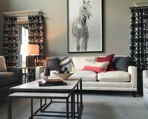 White sofa with red and charcoal pillows, nested metal coffee tables and a horse drawing above