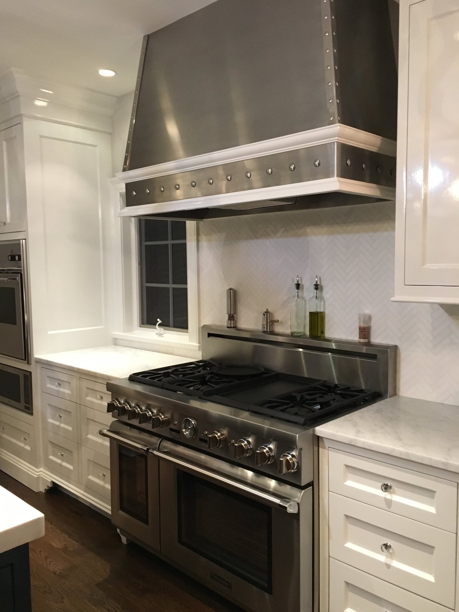 Rye kitchen with a studded stainless range hood above a professional range