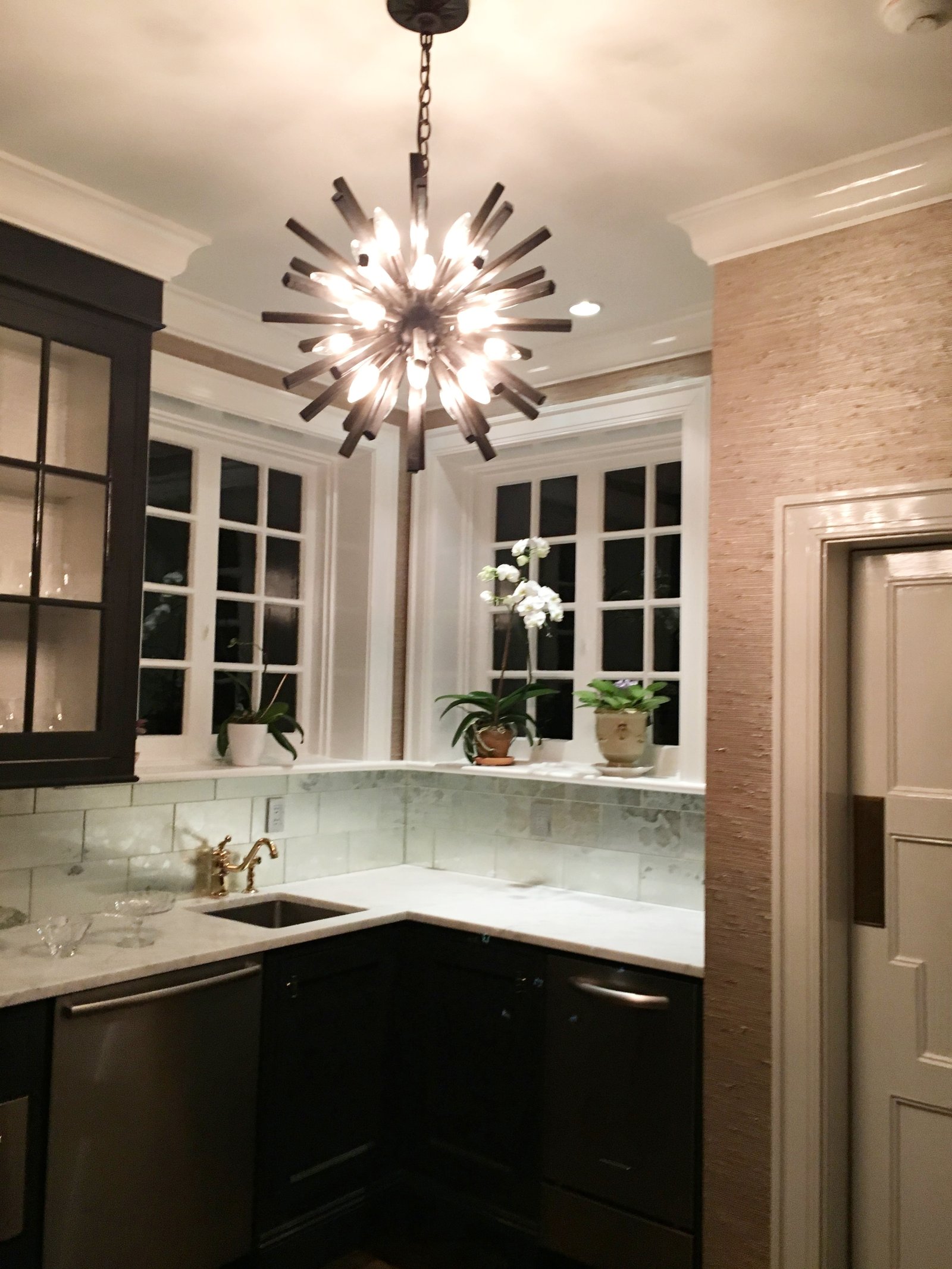 Butler’s pantry with dark cabinetry, marble counters and a sputnik chandelier