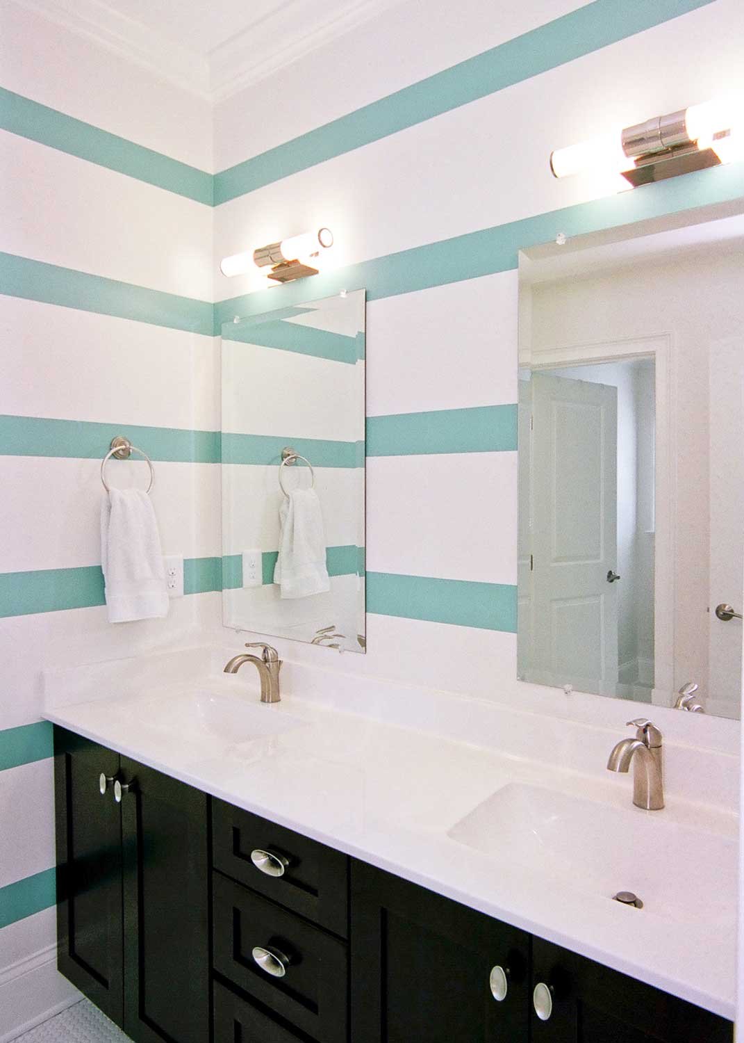 Bathroom with aqua-striped walls, a black double vanity and white quartz counters
