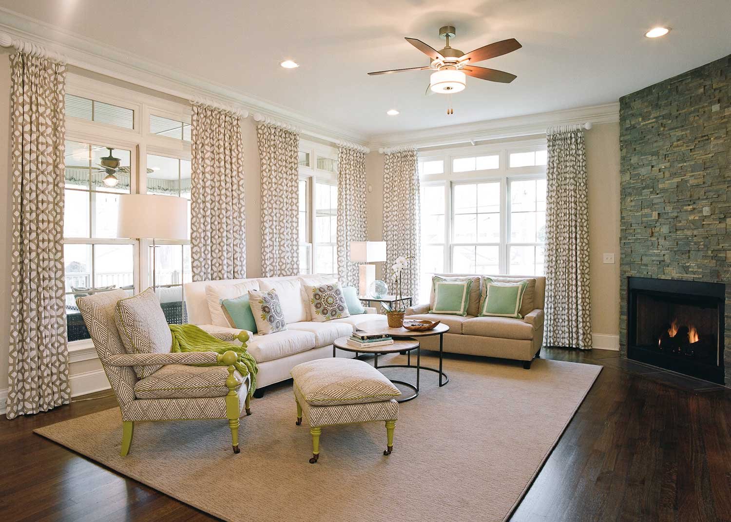 Light-filled living room in a newly built Greensboro home, with patterned draperies, a stacked-stone fireplace and chartreuse accents