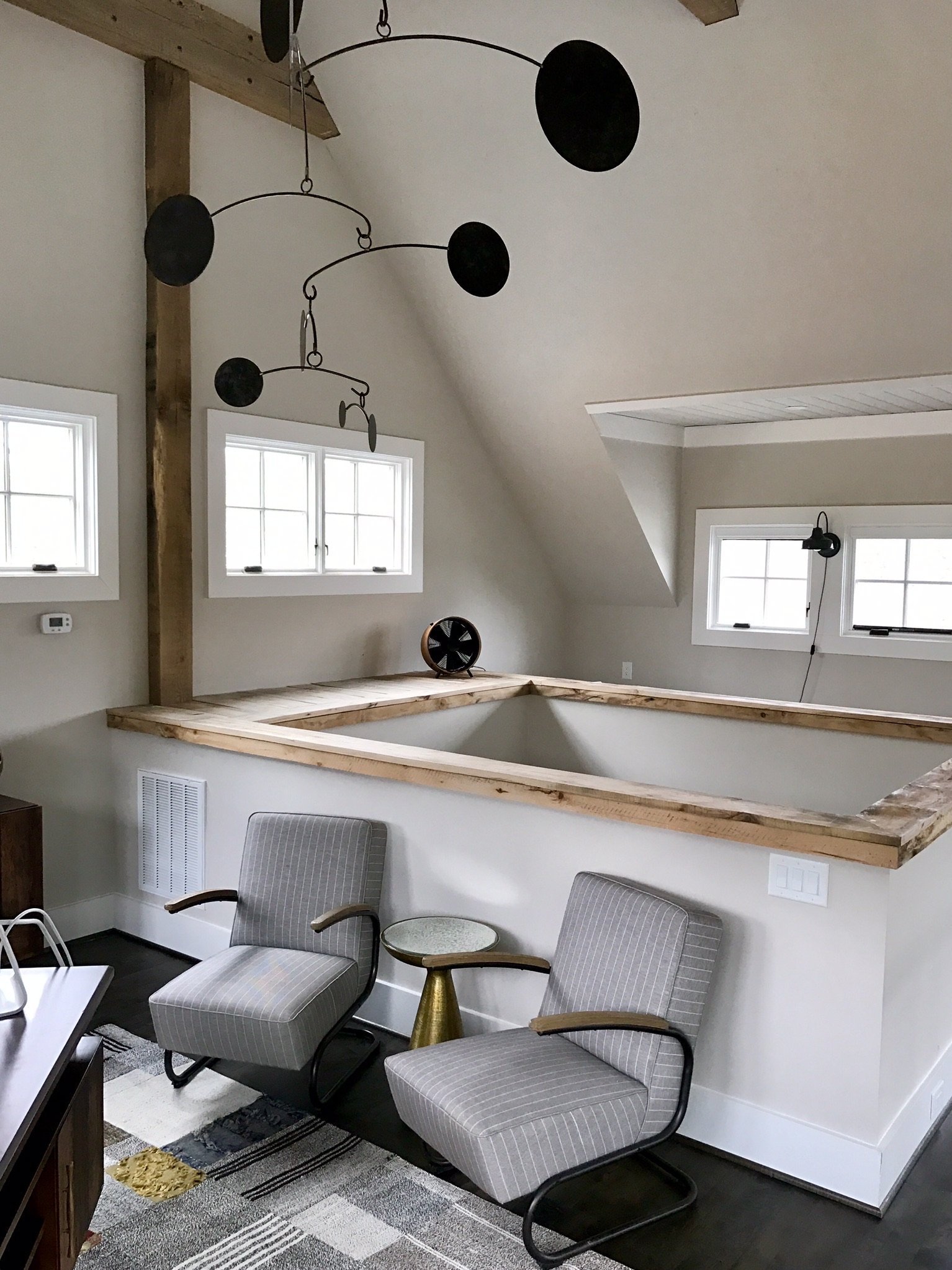 Light-filled attic retreat with exposed timber beams, dormer windows and a sculptural black mobile