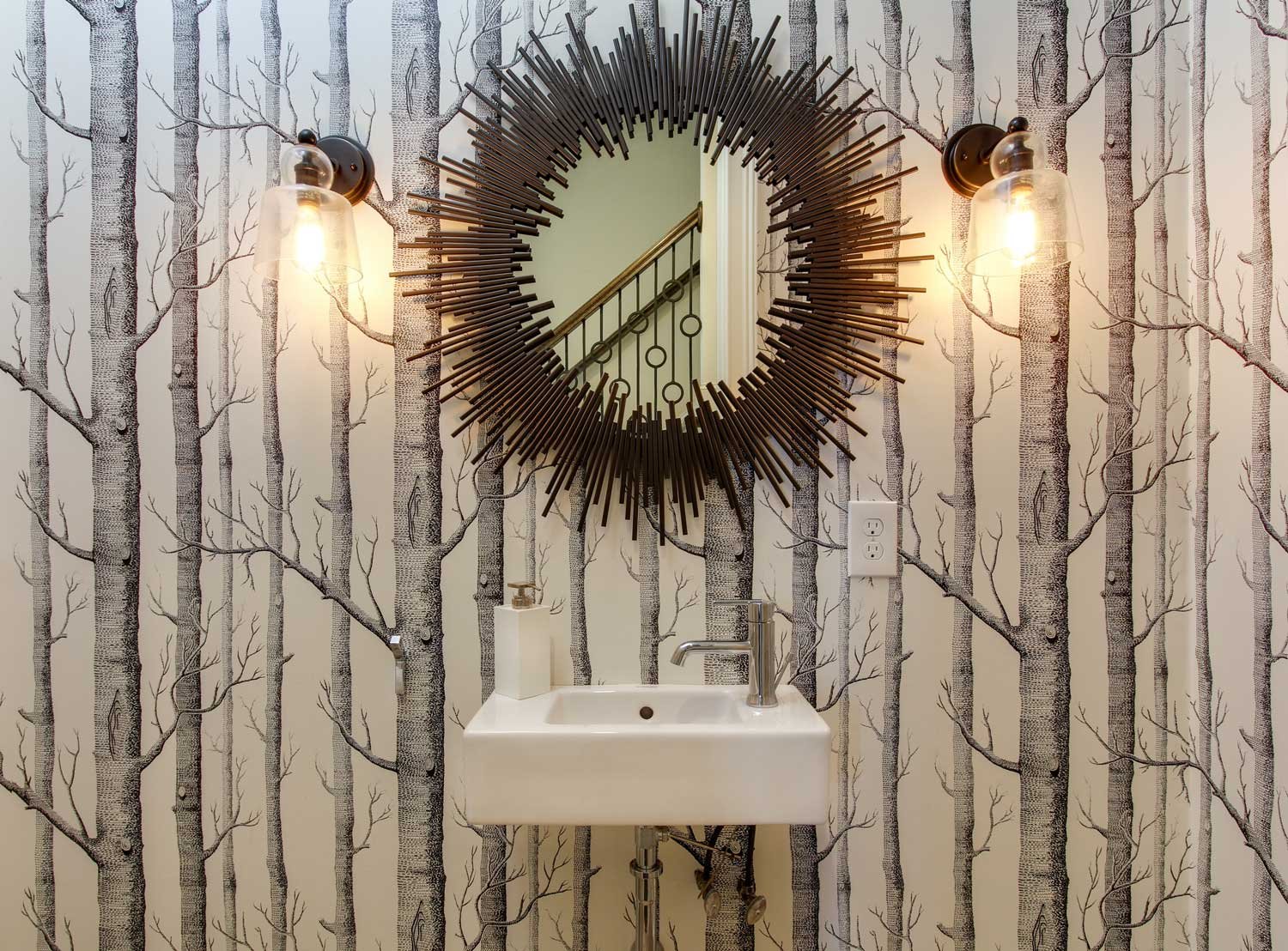 Powder room with birch-tree wallpaper, a spiky sunburst mirror, glass sconces and a floating white sink