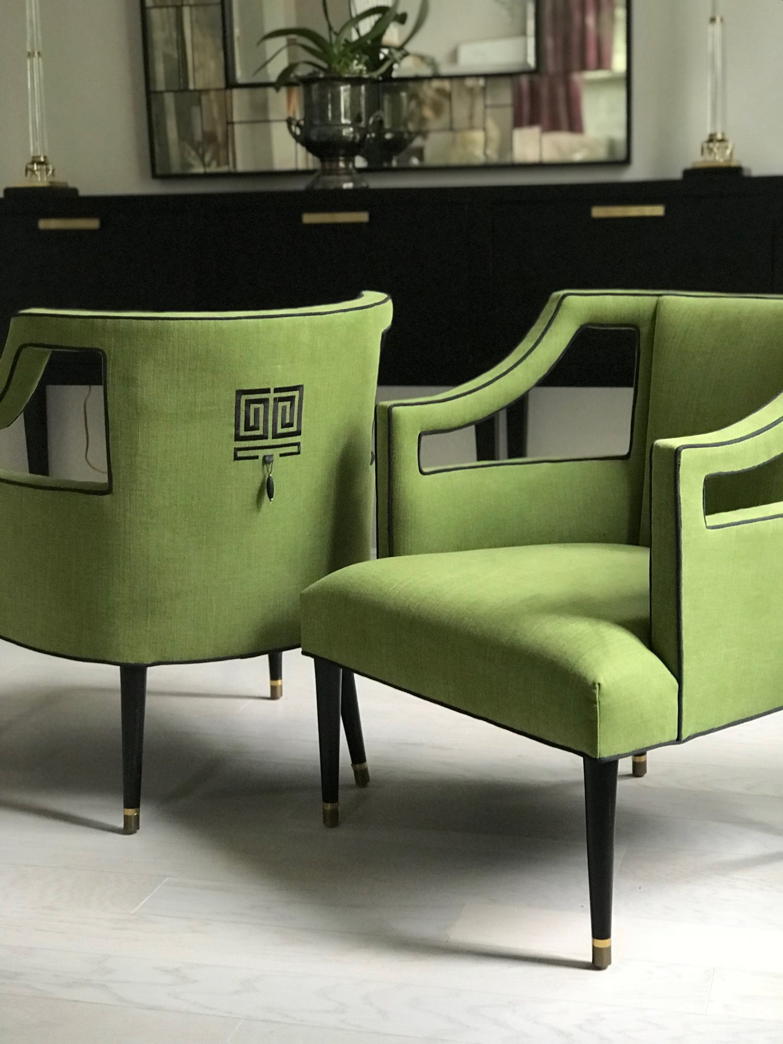 Pair of chartreuse linen barrel chairs with cut-out arms, black piping, a Greek-key embroidered back and brass-capped legs