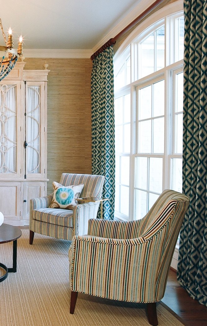 Striped armchairs beside the arched window and teal geometric drapery
